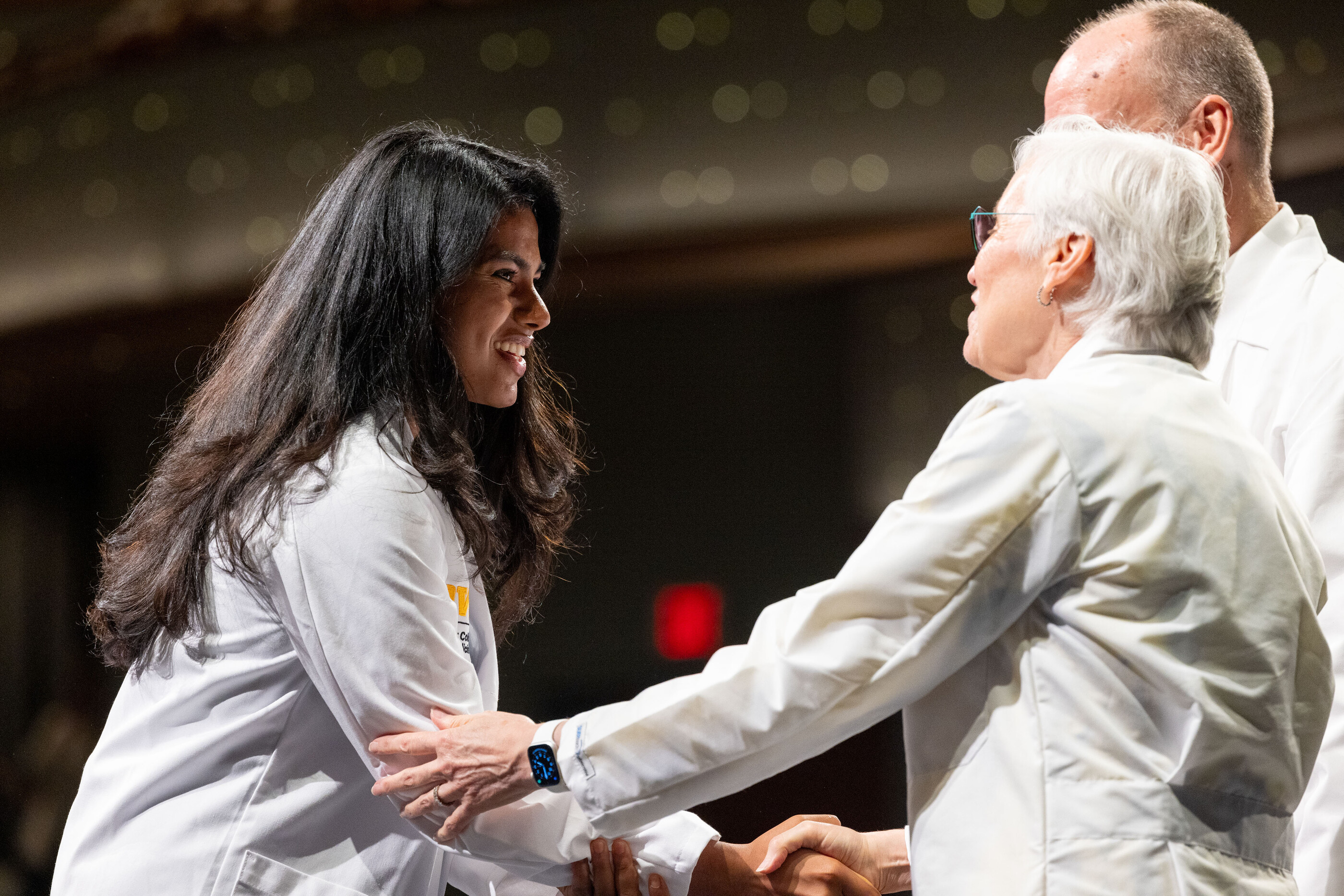 A student shakes hands with Pat Winokur during the White Coat ceremony.