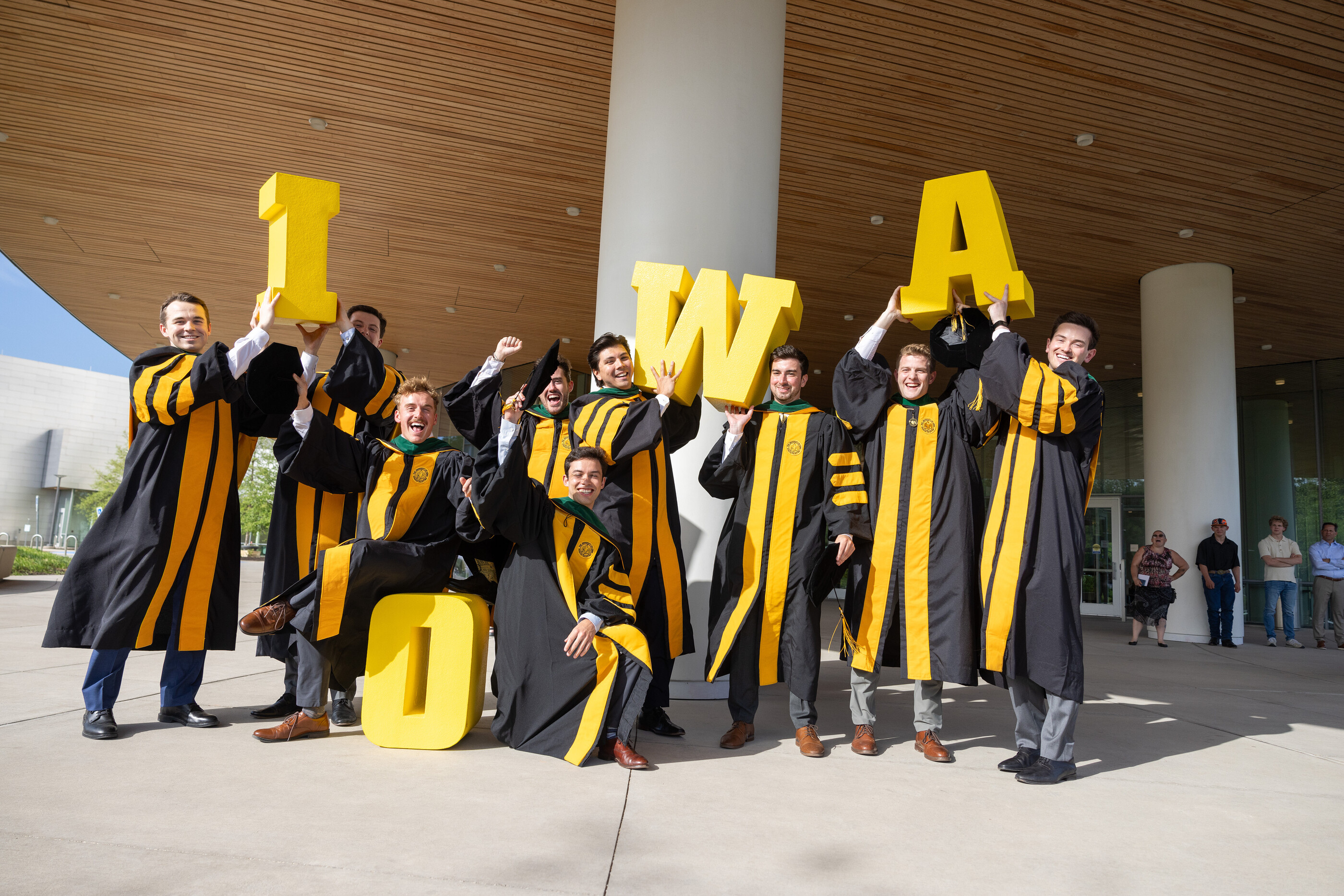 MD Commencement graduates holding Iowa letter props.