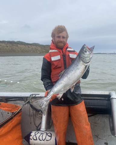 Troy Nation standing on a boat holding a large salmon