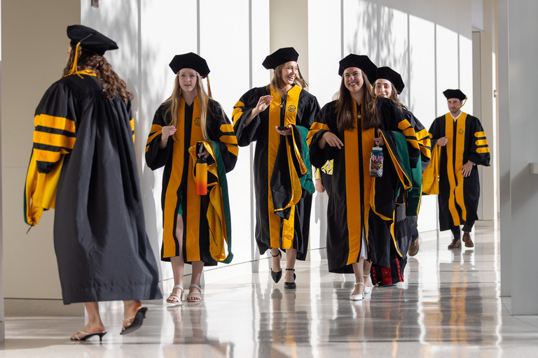 MD graduates walk down a hallway together.