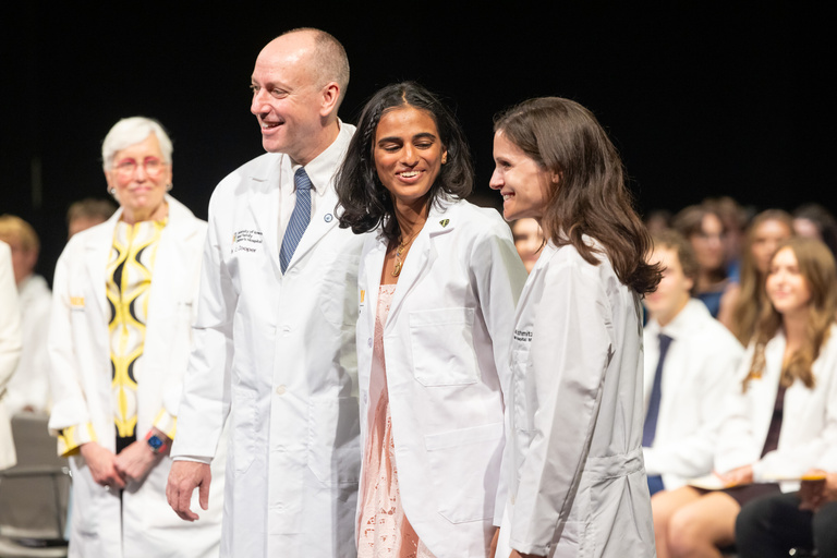 Student with faculty on the white coat ceremony stage.