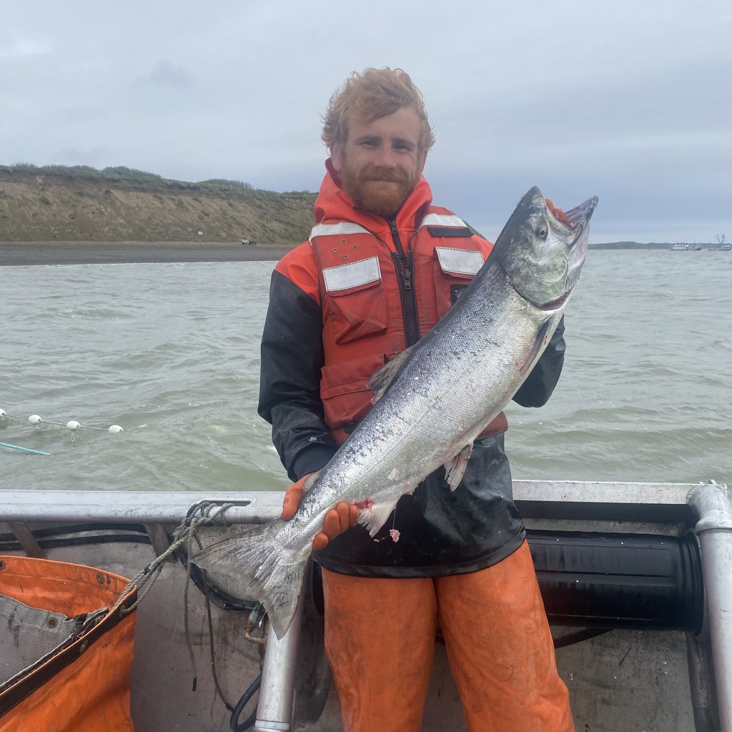 Troy Nation standing on a boat holding a large salmon